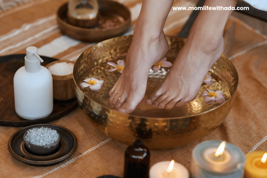 mom soaking feet in warm water with Epsom salt and candles nearby as a cozy self-care idea