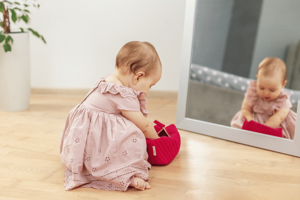 sensory play activities for babies — baby looking at reflection in large baby-safe mirror on floor