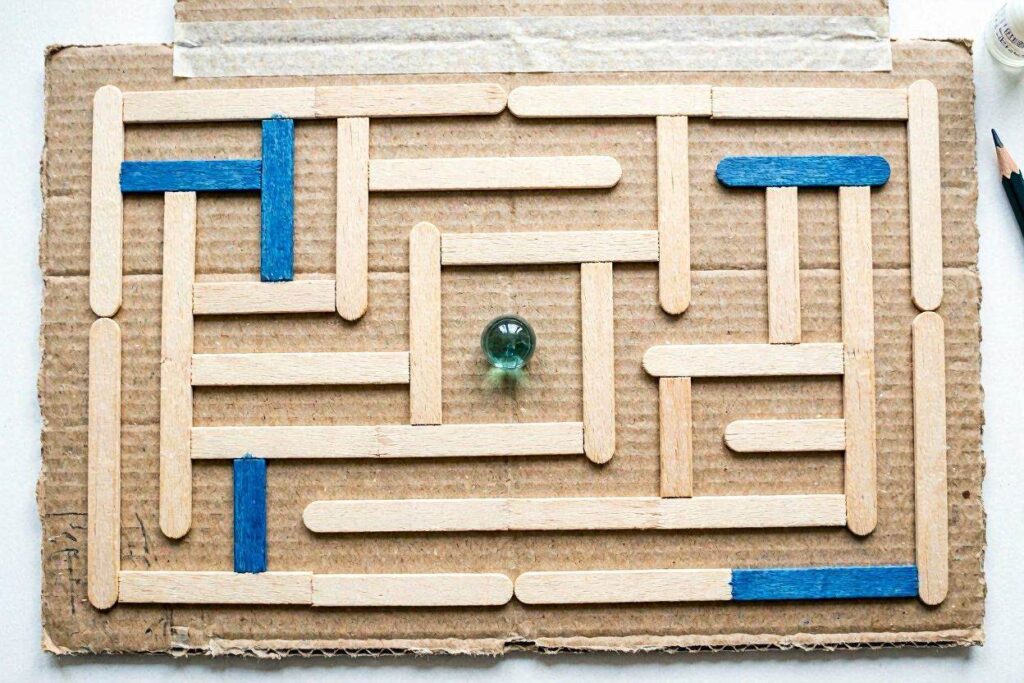 popsicle stick marble maze craft for kids on cardboard base"