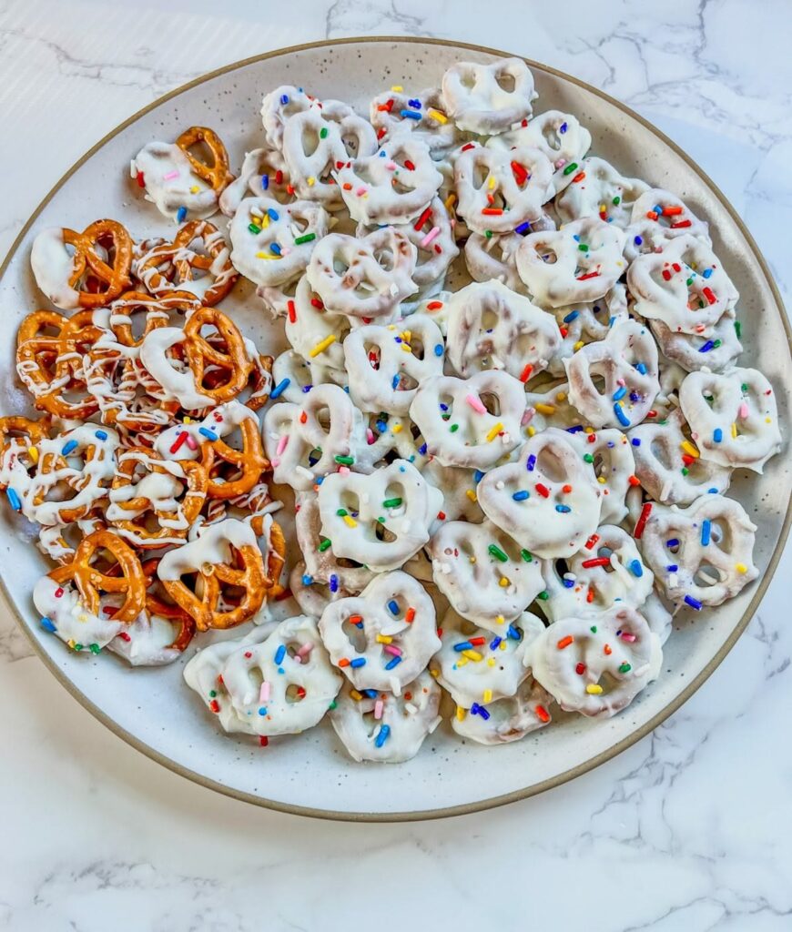 Homemade chocolate dipped pretzel rods with holiday sprinkles as Christmas gift treats