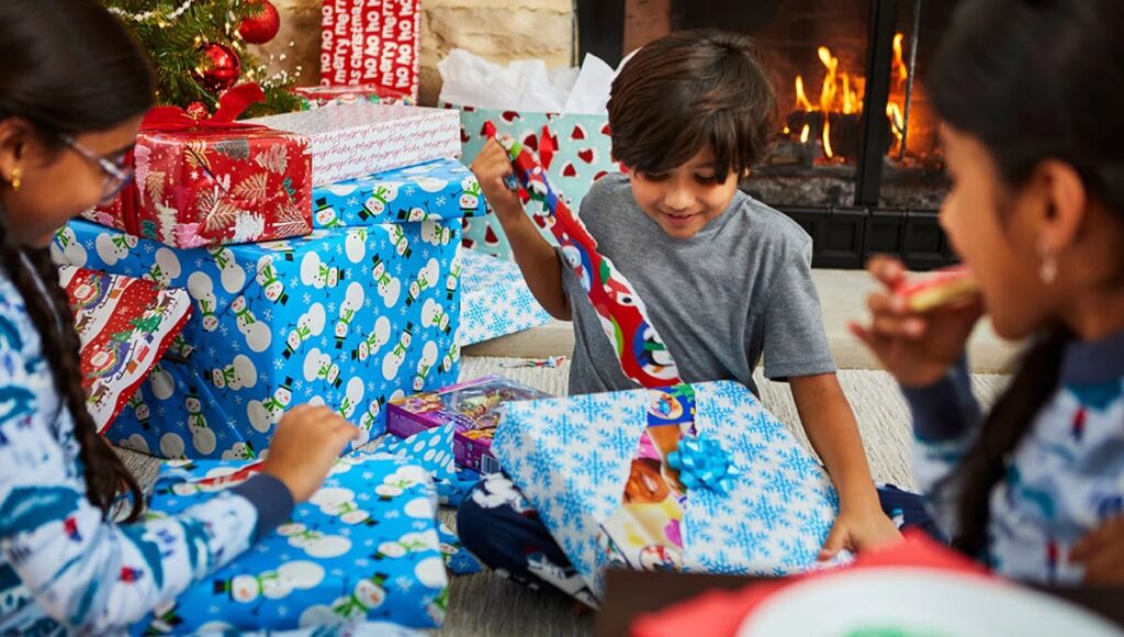 child opening a Christmas gift one at a time while family watches, Christmas Day gift traditions